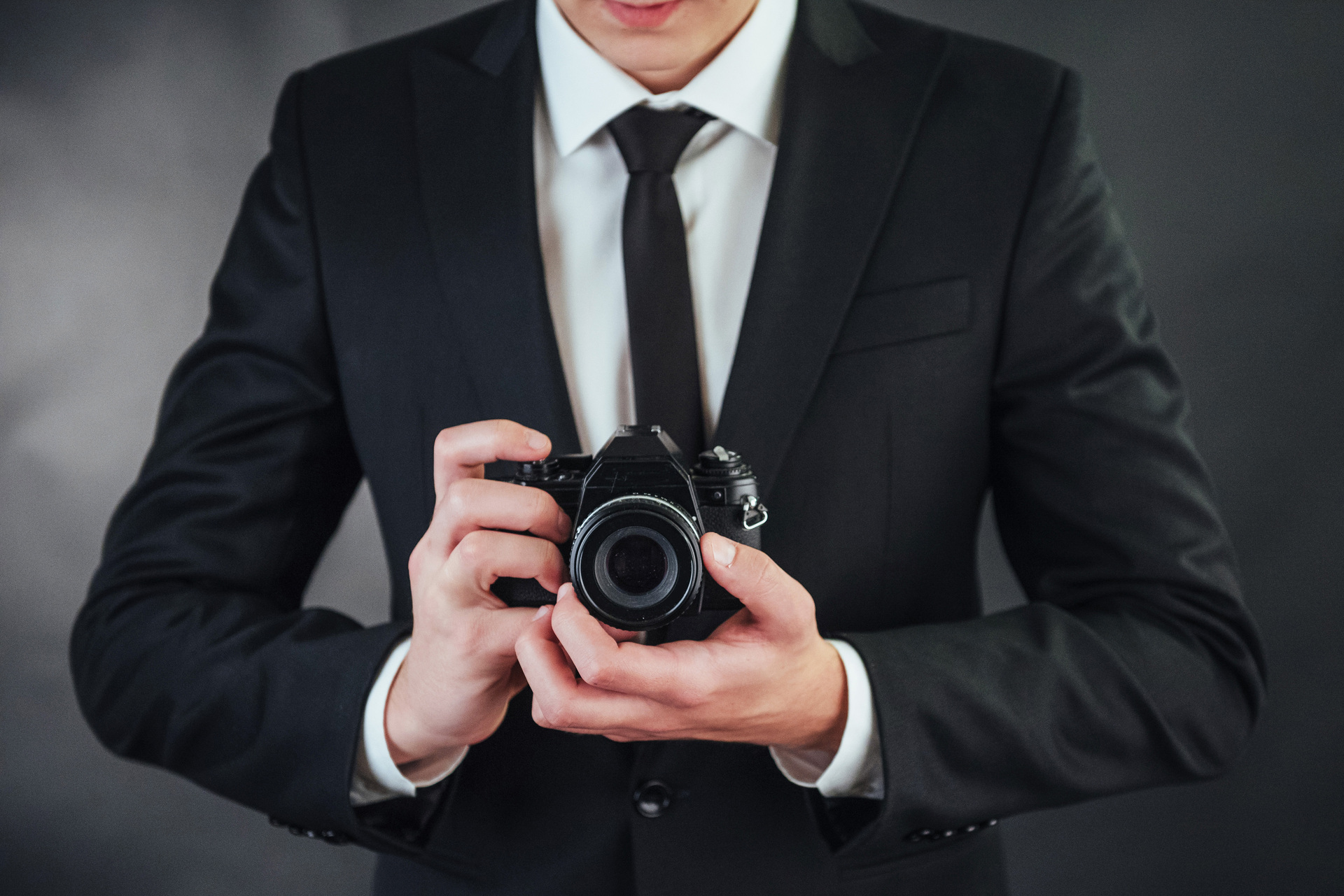 Mężczyzna w garniturze trzyma czarną cyfrowy aparat do robienia zdjęć portretowych